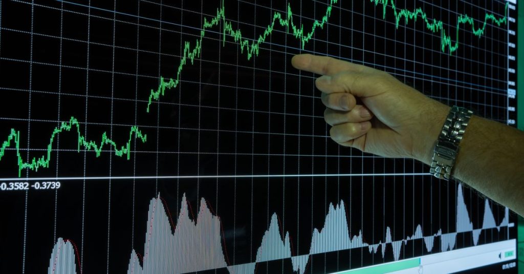 Gráfico que mostra a análise de dados financeiros com uma mão apontando para as tendências de mercado.